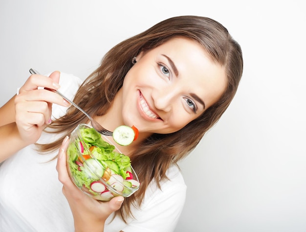 Ragazza con un'insalata su sfondo bianco