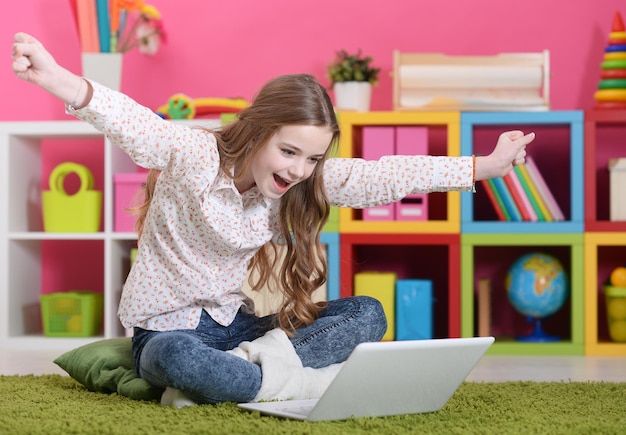 Ragazza con un laptop seduta sul tappeto