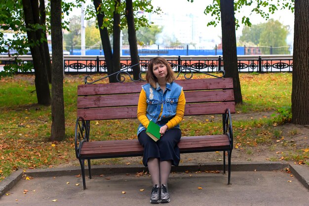 Ragazza con un libro nel fogliame di autunno