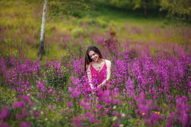 Ragazza con un mazzo di fiori, prato verde, fiori viola e rosa