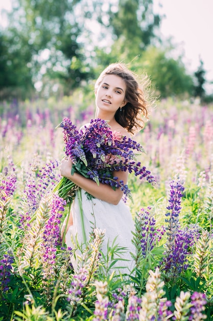 Ragazza con un mazzo di lupino sul campo