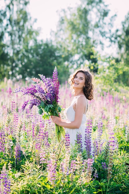 Ragazza con un mazzo di lupino sul campo