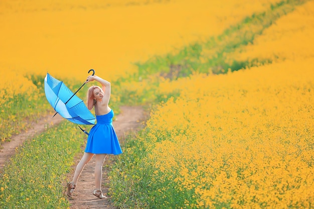 ragazza con un ombrello in un campo estivo di fiori, paese femminile natura campo giallo