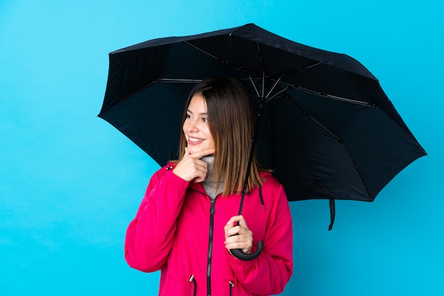 Ragazza con un ombrello sopra la parete blu