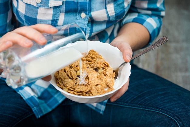 Ragazza con un piatto di cereali integrali e latte