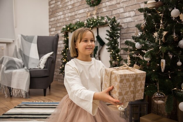 Ragazza con un regalo all'albero di Natale