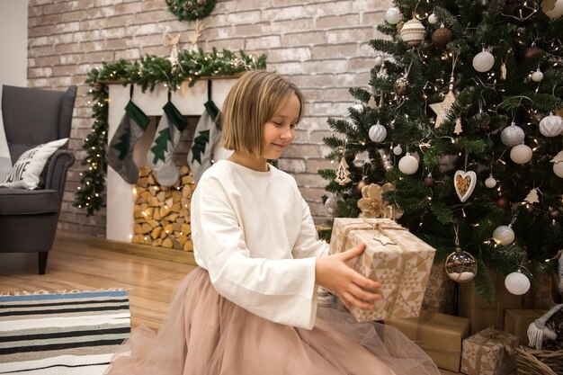 Ragazza con un regalo all'albero di Natale