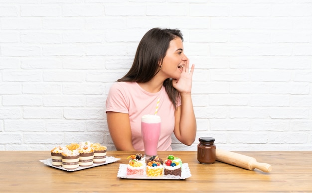 Ragazza con un sacco di mini torte diverse che grida con la bocca spalancata