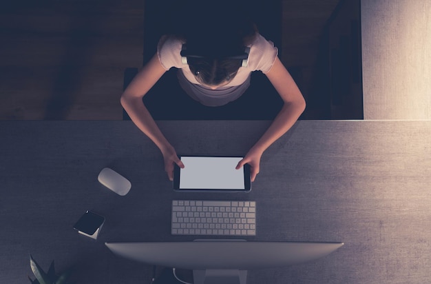 Ragazza con un tablet e le cuffie che studia alla sua scrivania