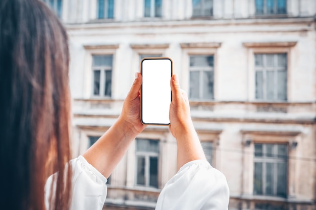 Ragazza con un telefono con uno schermo in mano sullo sfondo di un vecchio edificio