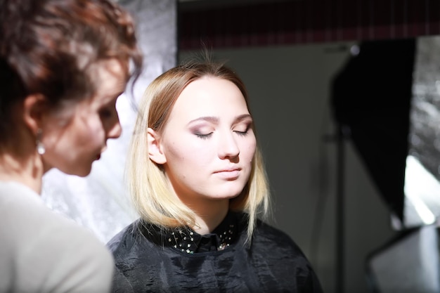 Ragazza con un truccatore in studio davanti a uno specchio