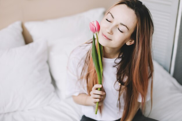 Ragazza con un tulipano rosa a letto