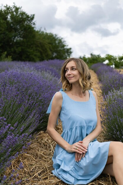 Ragazza con un vestito blu in un campo di lavanda girato in estate