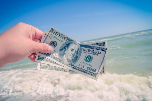 Ragazza con una banconota da 300 dollari sullo sfondo delle onde del mare