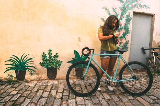 Ragazza con una bicicletta su una strada acciottolata di fronte a un muro Spazio copia Concetto di stile di vita