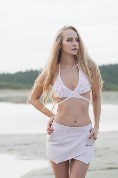 Ragazza con una figura perfetta in un costume da bagno rosa sulla spiaggia