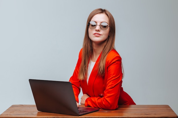 Ragazza con una giacca rossa e occhiali con un laptop