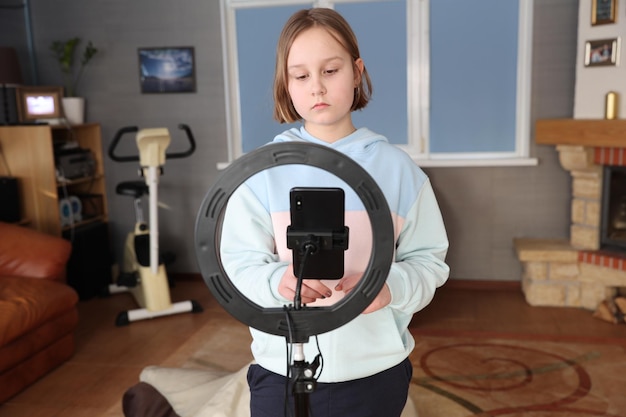 Ragazza con una lampada ad anello per una formazione a distanza su smartphone