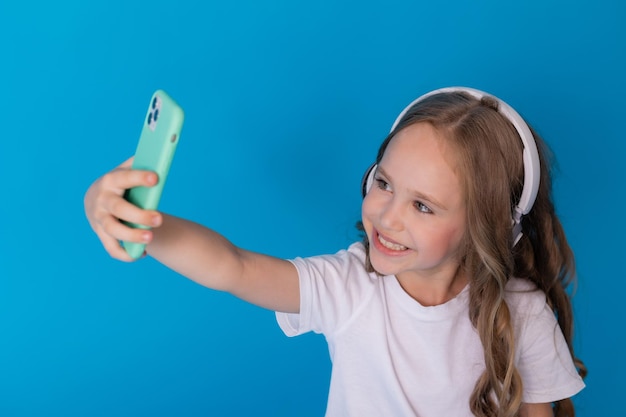 ragazza con una maglietta bianca e jeans con le cuffie sul suo smartphone si fa un selfie seduta sul pavimento