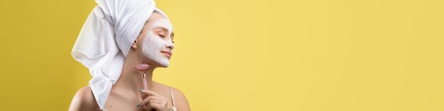 Ragazza con una maschera cosmetica sul viso in un asciugamano bianco