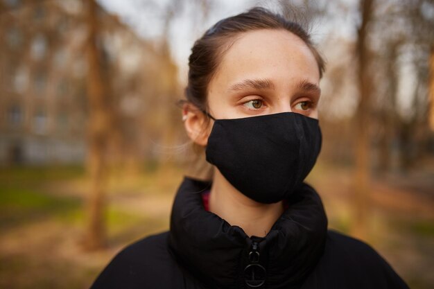 ragazza con una maschera medica nera sulla strada quarantena Autoisolamento