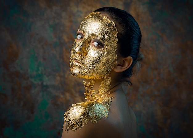 Ragazza con una maschera sul viso in foglia d'oro.