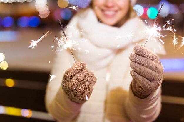 Ragazza con una stella filante in mano all'aperto inverno città sfondo neve fiocchi di neve