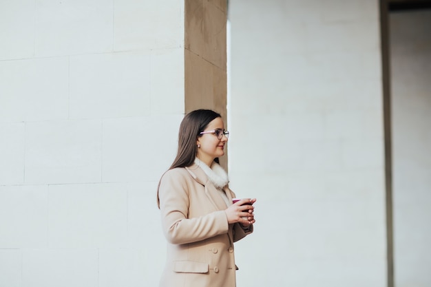 ragazza con una tazza di caffè a piedi in città