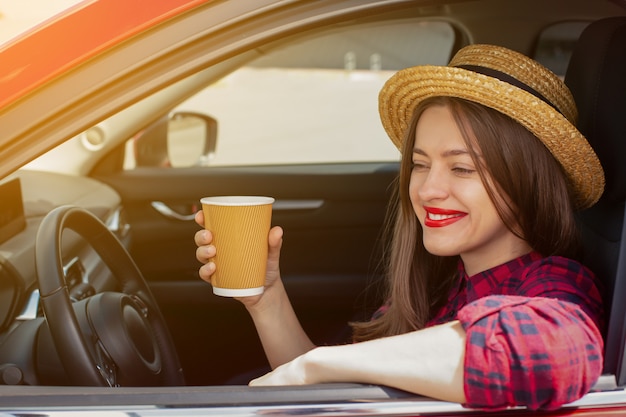 Ragazza con una tazza di caffè in auto