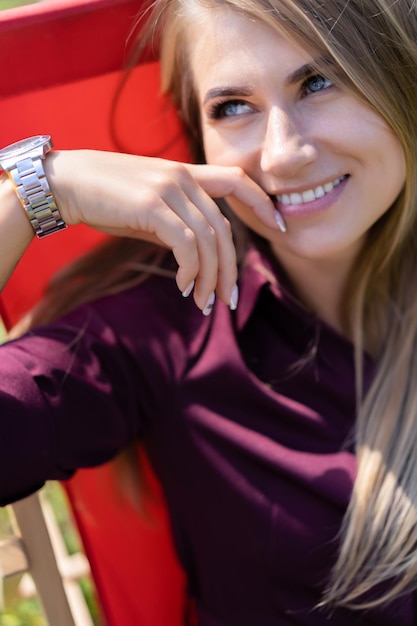 ragazza con uno smartphone e un cocktail sulla natura su una sedia a sdraio. Giornata estiva libera.