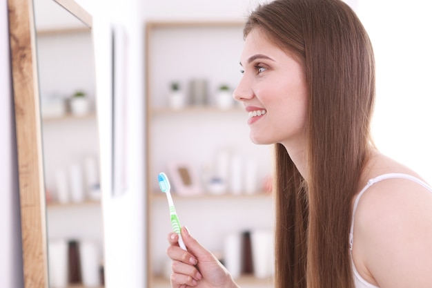 Ragazza con uno spazzolino da denti su uno sfondo chiaro