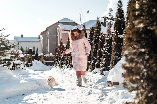 Ragazza con uno spitz di cucciolo di cane che gioca nel divertimento all'aperto di inverno