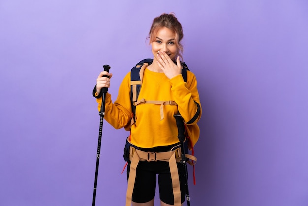 ragazza con zaino e bastoncini da trekking sulla bocca isolata viola felice e sorridente coning con la mano