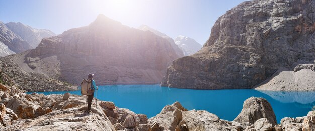 Ragazza con zaino vicino al lago Big Alo sullo sfondo di montagna rocciosa. Monti Fann, Tagikistan, Asia centrale