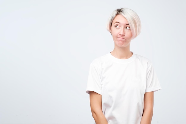 Ragazza confusa preoccupata con i capelli corti e colorati e le lentiggini carine che guarda da parte vedendo la reazione nervosa