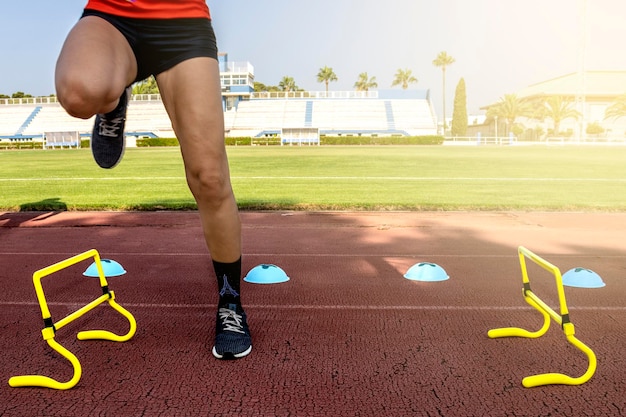 Ragazza corridore che salta gli ostacoli sulla pista sportiva Concetto di sport