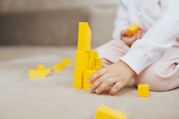 ragazza costruire edificio da blocchi di costruzione giocattolo giallo