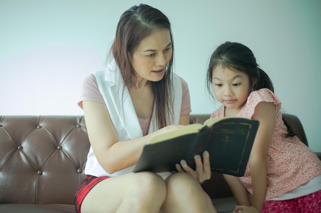 Ragazza cristiana religiosa che legge la Bibbia con la madre all'interno