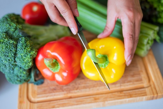 ragazza cuoca in cucina taglia la paprika rossa con le verdure con un coltello