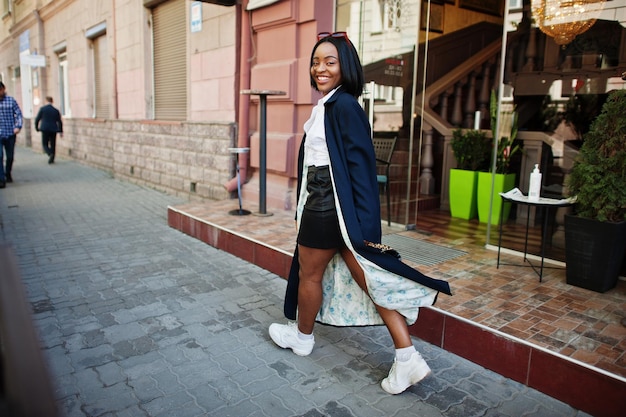 Ragazza d'affari africana chic in cappotto con borsetta Ritratto di strada alla moda di donna afroamericana