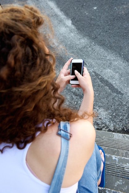 Ragazza da dietro che tiene cellulare e mandare SMS