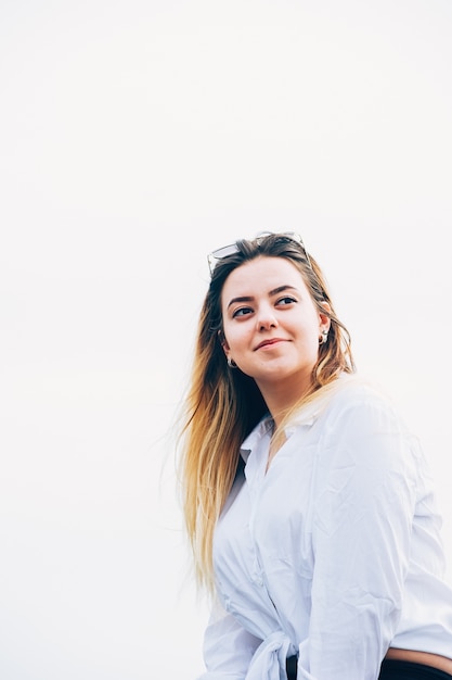 ragazza dai capelli abbastanza lunghi dentro in camicia bianca che sorride felicemente