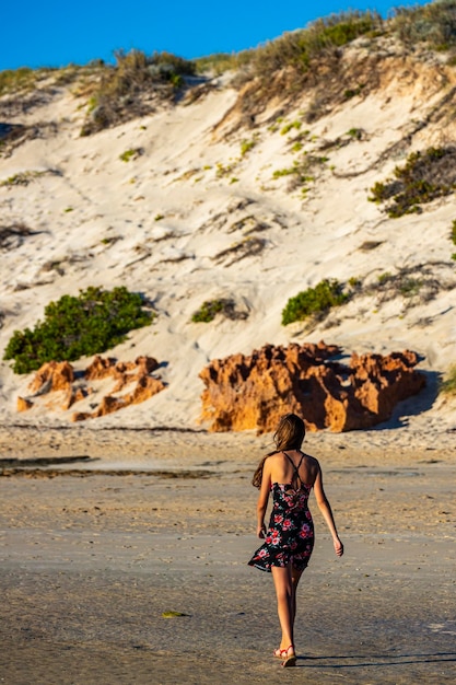 ragazza dai capelli lunghi in abito nero cammina sulla spiaggia di Coral Bay al tramonto, spiaggia dell'Australia occidentale