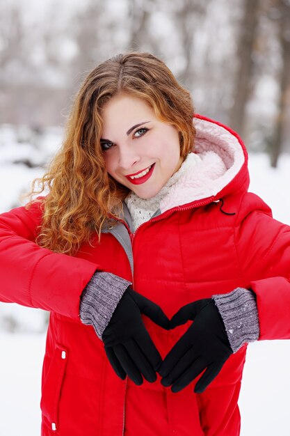 Ragazza dai capelli rossi che mostra un cuore con le sue mani il giorno di San Valentino