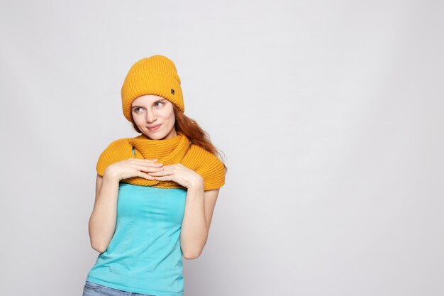 Ragazza dai capelli rossi con un cappello caldo su uno sfondo chiaro