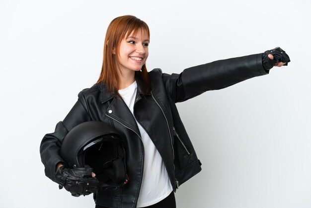 Ragazza dai capelli rossi con un casco da motociclista isolato su sfondo bianco che fa un gesto di pollice in alto