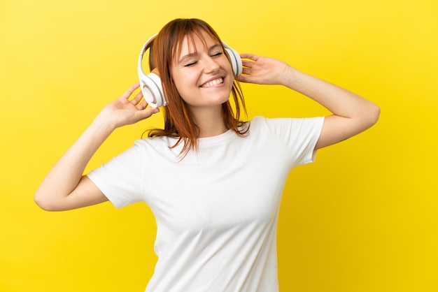 Ragazza dai capelli rossi isolata su sfondo giallo ascoltando musica