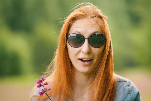 Ragazza dai capelli rossi sorpresa al campo di fiori, giorno d'estate