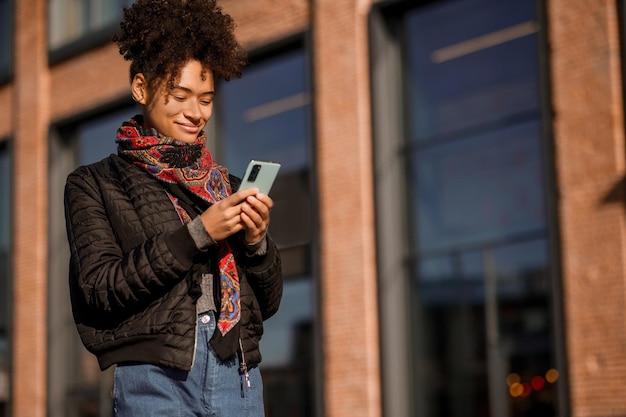 Ragazza dai capelli scuri in giacca e jeans in strada