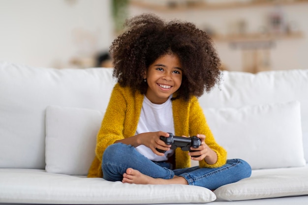 Ragazza del bambino afroamericano felice del preteen che gioca al videogioco